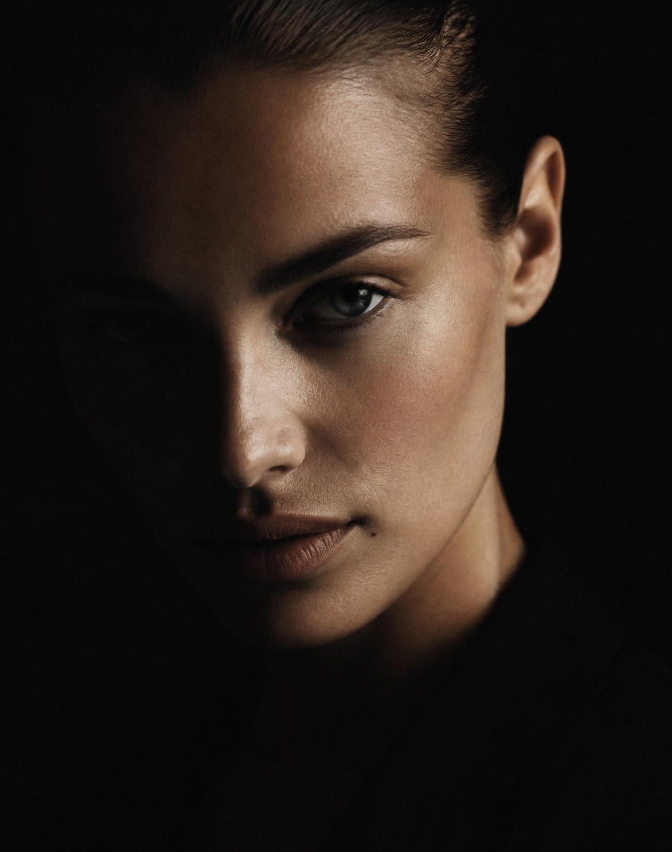Editorial portrait lit from one side against black
